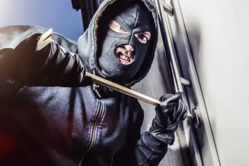 Einbrecher beim Aufhebeln einer Tür mit einem Brecheisen